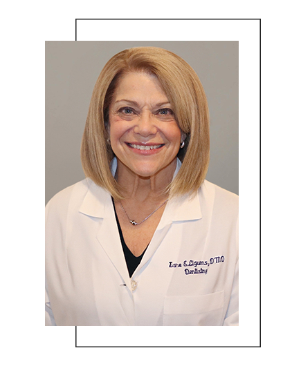 The image shows a woman with short hair wearing a white lab coat, posing for a portrait.