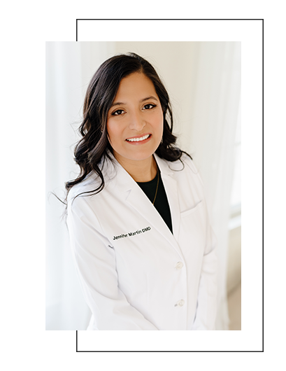 The image shows a woman wearing a white lab coat, smiling at the camera, with her name and title visible on the lab coat.